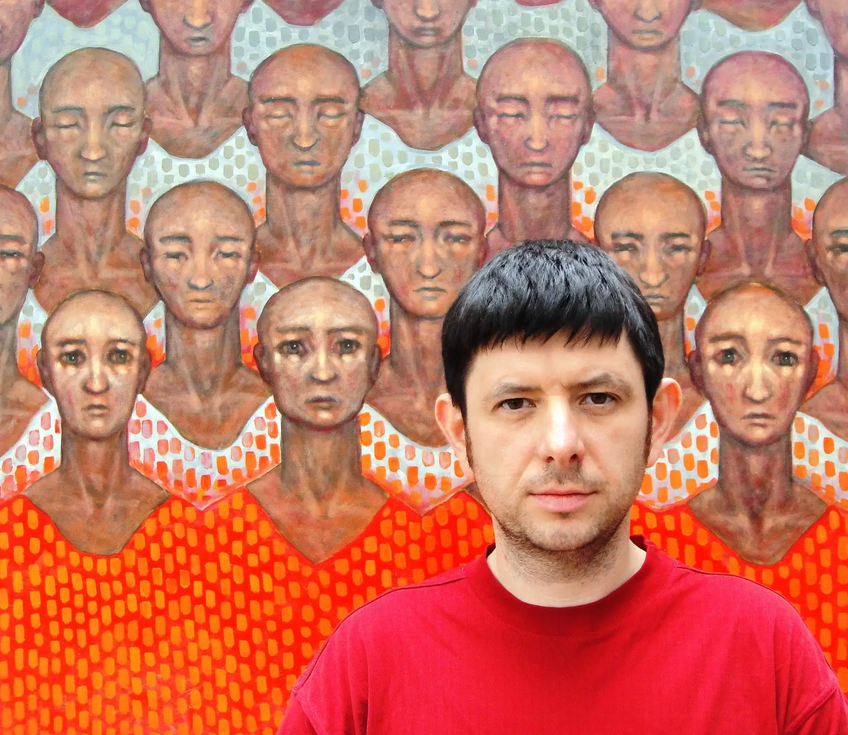 Photograph of Ihor Polishchuk infront of a self-portrait.